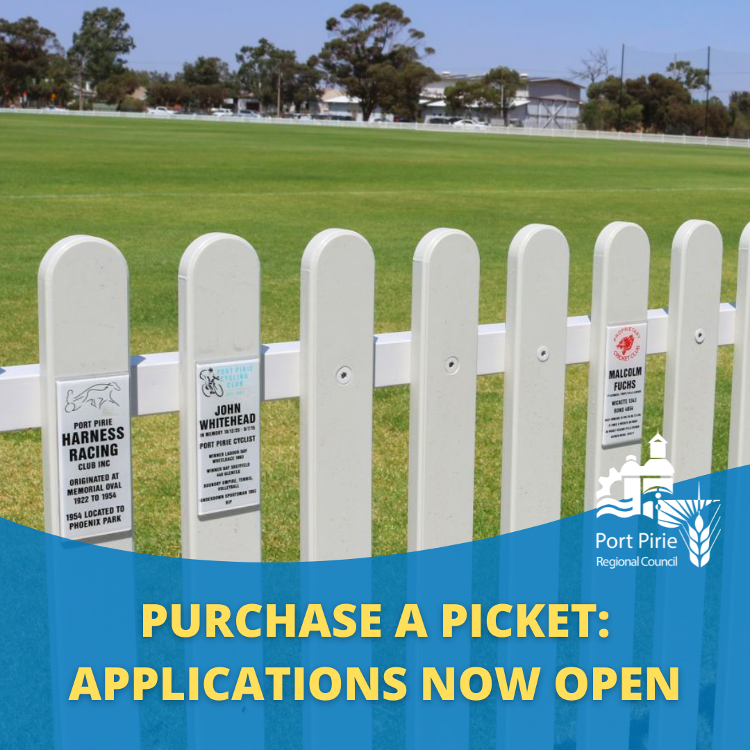 image of white picket fence with green grass of memorial oval in background